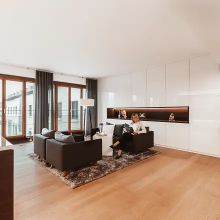 Moderner und heller Büroraum mit großen Fenstern, stilvollen Möbeln und einer Person bei der Arbeit. Ideal zum Büro mieten in Berlin Mitte, Pariser Platz 6a.