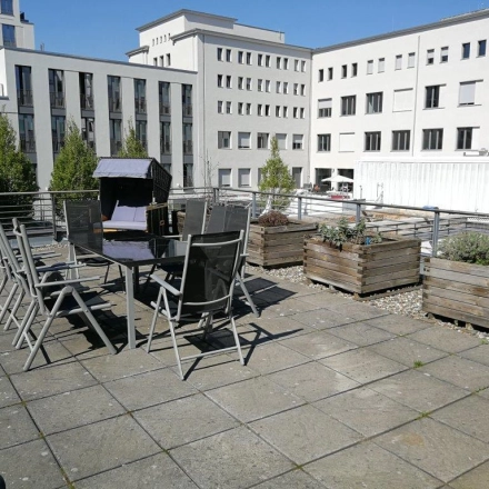 Rooftop-Terrasse mit Tischen und Stühlen in Berlin Mitte, ideal, um nach dem Büro mieten eine Pause an der frischen Luft zu genießen.