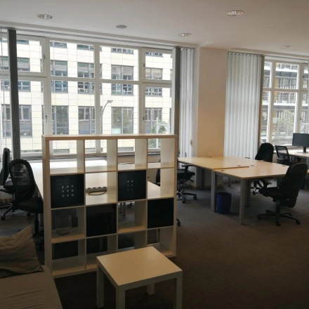 Helles Büro in Berlin Mitte mit großen Fenstern, mehreren Arbeitsplätzen und einer Couch; ideal zum Büro mieten.