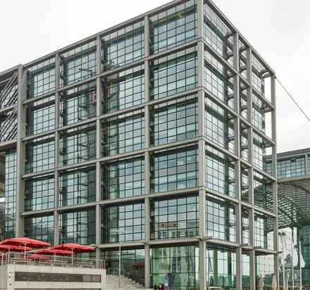 Moderne Bürogebäude am Europaplatz 2, Berlin Moabit, geeignet für büro mieten oder bürofläche mieten, angrenzend an den belebten Hauptbahnhof mit Glasfassaden und überdachtem Eingangsbereich.