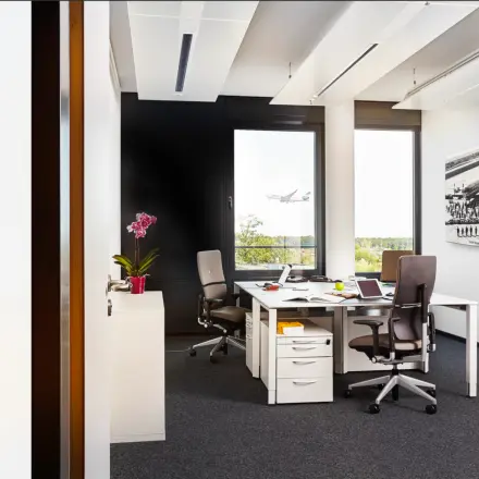 Modernes Büro in der Solmsstraße 83, Frankfurt Bockenheim, mit stilvoller Einrichtung, zwei Schreibtischen und Blick auf einen startenden Flugzeug für effizientes Arbeiten. Perfekt für Büro mieten oder Büroraum mieten.