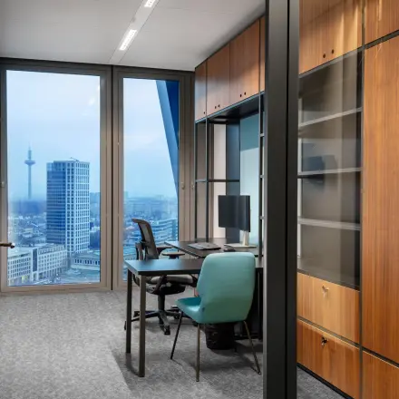 Modernes Büro mit Blick auf die Skyline in der Junghofstraße 9, Frankfurt Innenstadt. Ideal für Bürofläche mieten mit Schreibtischen, Stühlen und einem eleganten Holzschrank.