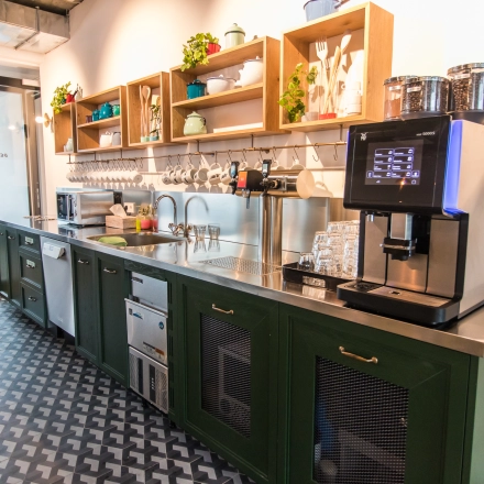 Moderne Büro-Pantry in der Herzogspitalstraße 24, München Altstadt mit stilvollen, offenen Regalen und einem Kaffeeautomaten, ideal für Mieter, die büroraum mieten wollen.