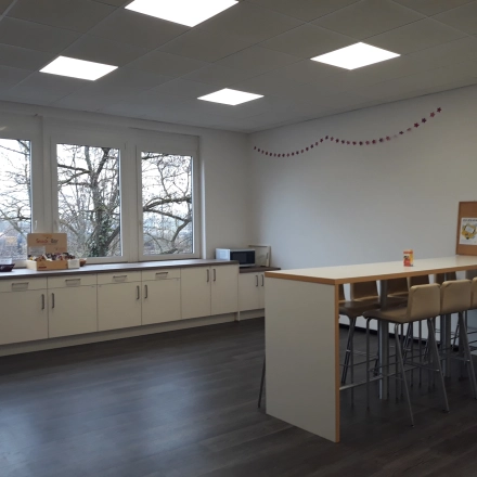 Heller Büroraum in München Pasing mit großen Fenstern und minimalistischem Mobiliar, ideal für Pausen. Perfekt für alle, die Bürofläche mieten oder Büroraum mieten möchten.