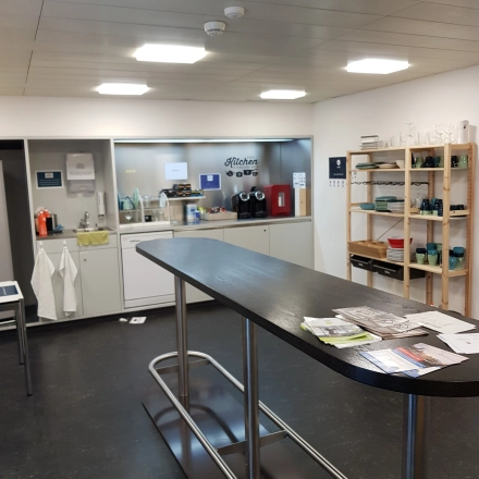 Möblierte Pantry mit hohen Tischen und Regalen in Mythenquai 26, Zürich Enge. Perfekt, um als Bürofläche zu mieten und für Pausen oder Meetings zu nutzen.