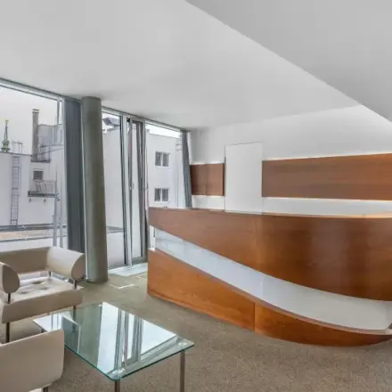 Modern office space at Mariahilfer straße 36, 1070 Vienna, featuring a stylishly furnished reception area with large windows and contemporary seating, available for rent.