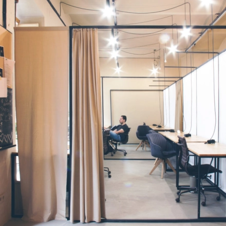 Modern office space with workstations and a person engaged in business activities at Zimmermanngasse 8, 1090 Vienna. Ideal office to rent with sleek design.
