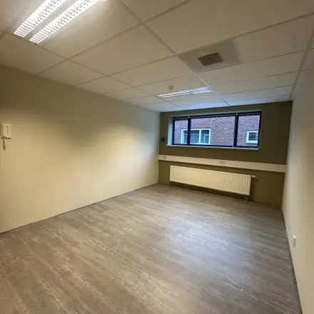 Empty office space at Hollandse Kade 38, Abcoude, featuring a neutral-toned interior with large window and overhead lighting, available for rent. Ideal for setting up your next office to rent.