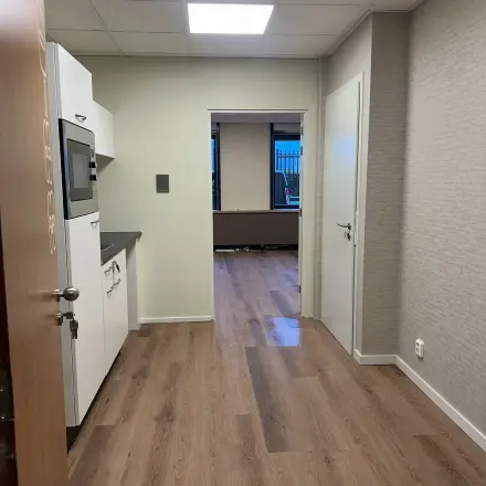 Interior view of a furnished office space available for rent at Hollandse Kade 38, Abcoude, featuring a kitchenette area with cabinets and wood-patterned flooring.