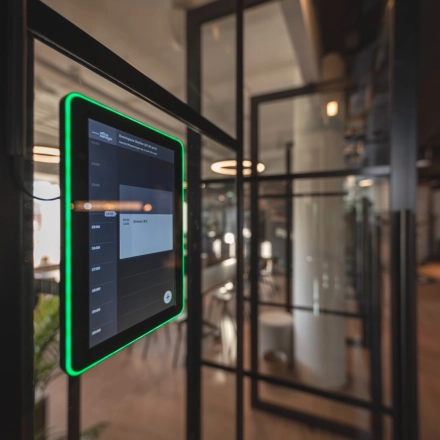 Modern office space for rent at Egbert Gorterstraat 2-14 in Almelo, featuring glass partitions and a digital schedule display panel, offering a tech-friendly environment.