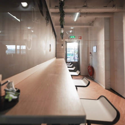 A sleek and modern open-floor workspace featuring a long wooden countertop with high stools, perfect for office space rental in Almelo's Egbert Gorterstraat 2-14.