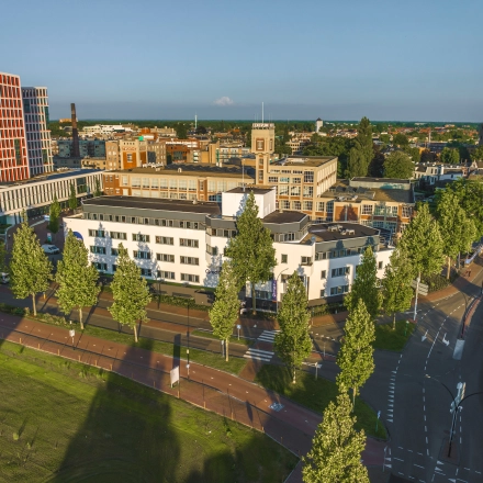 Aerial view of an office building at Egbert Gorterstraat 2-14, Almelo, surrounded by trees with roads running alongside. The space offers opportunities for office space rental in a bustling business district.