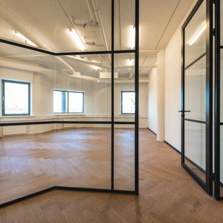 Modern, spacious office space rental at Egbert Gorterstraat 2-14 in Almelo, featuring large windows and stylish wooden flooring, offering natural light and a sleek design.