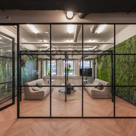 Modern office space rental featuring a stylish lounge area with comfortable seating and lush green walls at Egbert Gorterstraat 2-14, Almelo.
