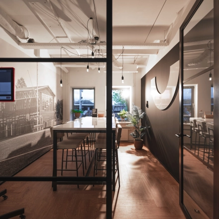 Modern office interior at Egbert Gorterstraat 2-14 in Almelo featuring a long table and high stools, suitable for dynamic meetings or as a collaborative workspace. Ideal for office space rental.