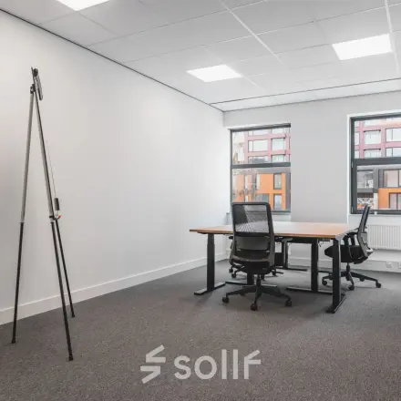 Furnished office space available for rent at Veluwezoom 15, Almere Stad, featuring desks and chairs set against large windows.