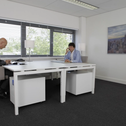 Two people work at a sleek table in a bright office at Europalaan 16, Alphen aan den Rijn, ideal for office space rental.
