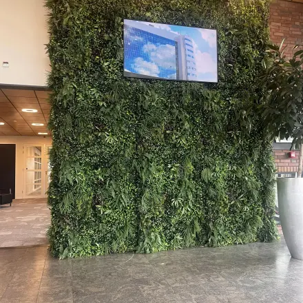 Bright lobby at Leidse Schouw 2, Alphen aan den Rijn with a lush green wall and TV screen, ideal for office space rental.