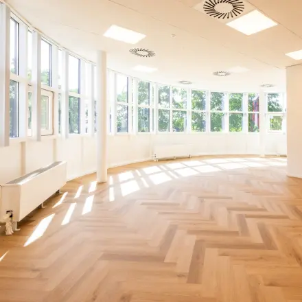 Spacious office space with large windows and wooden flooring at Maanlander 43, perfect for office space rental in Amersfoort Calveen.