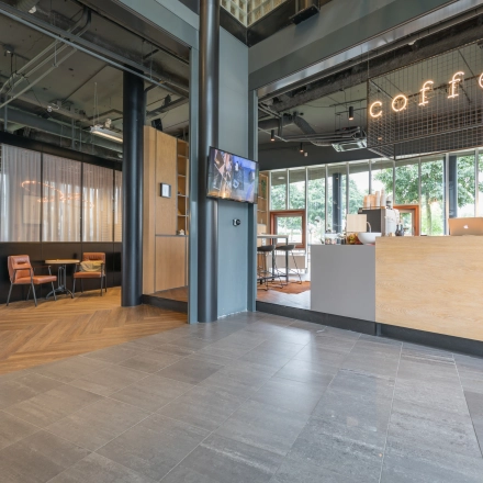 Modern office space rental at Maanlander 47 in Amersfoort Calveen featuring a welcoming area with seating and a coffee counter.