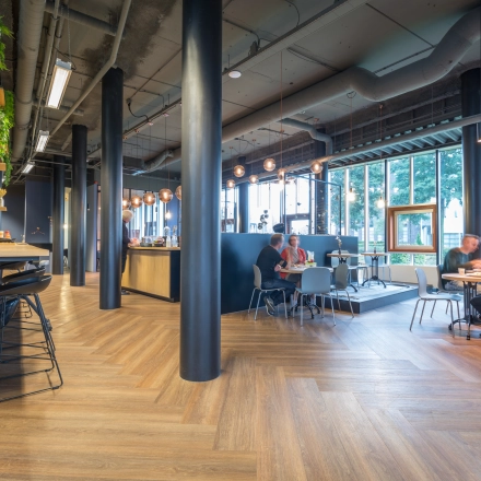 Modern office space at Maanlander 47, Amersfoort Calveen, featuring a furnished open floorplan with people engaging in discussions, ideal for rent office space needs.
