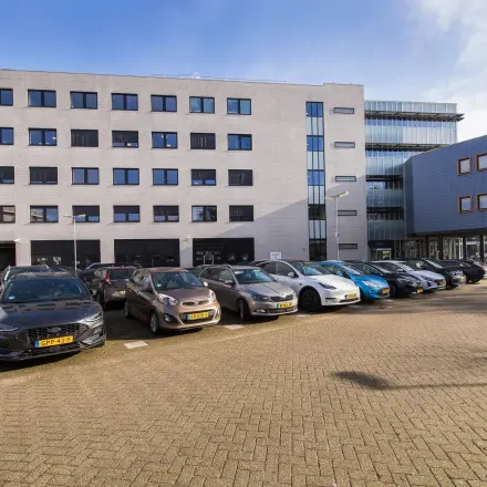 Exterior view of the office building at Maanlander 47, Amersfoort Calveen, showcasing the parking area. Ideal for those seeking office space rental with convenient access.