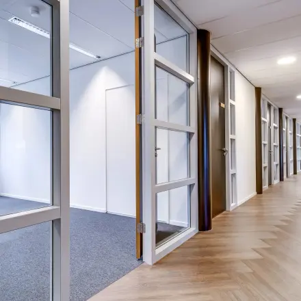 Spacious office for rent at Maanlander 47, Amersfoort Calveen, featuring a well-lit corridor and visible furnished workspace.