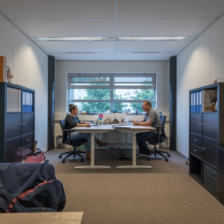 Two people working at desks in a furnished office space at Maanlander 47, Amersfoort Calveen, ideal for rent office space seekers.