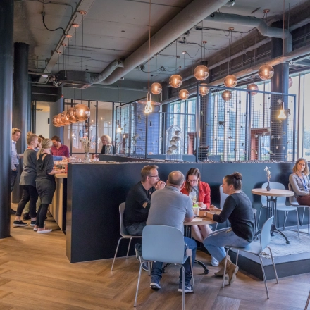 Modern interior at Maanlander 47, Amersfoort Calveen, with people engaging in conversations and enjoying the office lounge area. Ideal space for office space rental and networking.