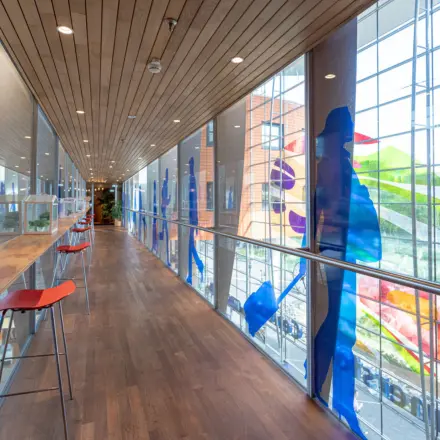 Bright corridor with high windows and colorful artwork at Amersfoort Centraal Station, ideal for break time in your rented office space.