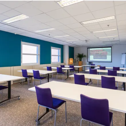 Bright office space with tables and purple chairs ideal for office space rental at Stationsplein 49, Amersfoort Centraal Station.
