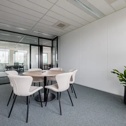 Modern office space for rent at Stadsring 201, Amersfoort Centrum, featuring a round table with chairs and stylish potted plants, perfect for meetings or collaborative work.