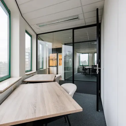 Bright, furnished office space available for rent in Amersfoort Centrum, featuring large windows and modern furnishings.
