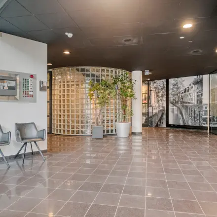 Spacious entrance area in a modern office to rent at Asch van Wijckstraat 2-4, featuring sleek tile flooring and a glass block wall for an open, professional feel.