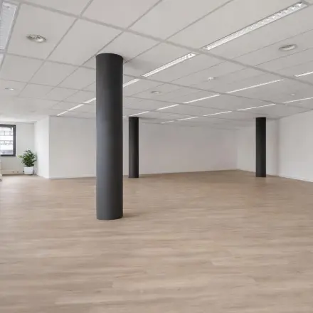 Spacious unfurnished office space with large windows and wooden flooring, ideal for office space rental in Amersfoort Centrum.