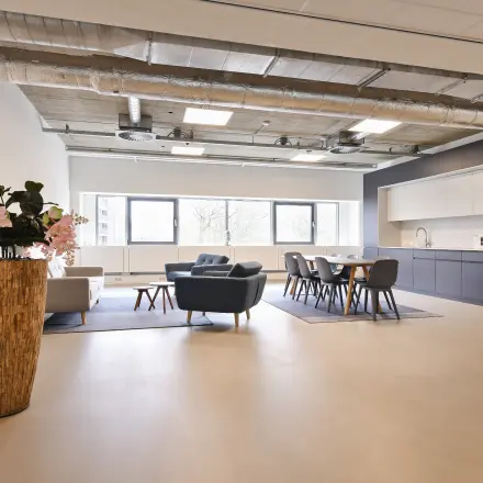 Amstelveen office to rent featuring a spacious, furnished open-floor layout with modern seating and kitchen area at Stroombaan 4.