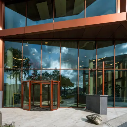Exterior view of the office building at H.J.E. Wenckebachweg 230-258, featuring a modern glass facade and revolving door. Ideal for office space rental in Amsterdam Amstel Business Park.