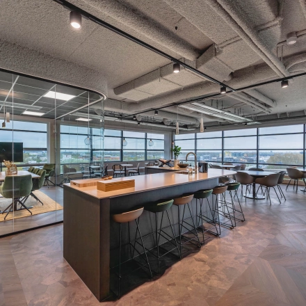 Bright, modern office space for rent at Joop Geesinkweg 201, located in Amsterdam Amstel Business Park, featuring a bar-style seating area and a conference room.