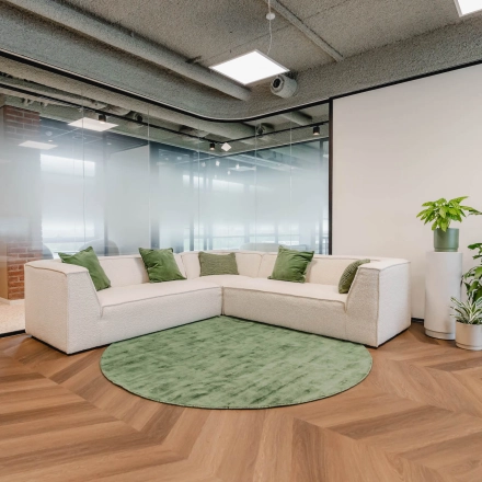 Modern office lounge with a corner sofa and greenery at Joop Geesinkweg 201, suitable for casual meetings or breaks. Consider this inviting option for office space rental in Amsterdam Amstel Business Park.