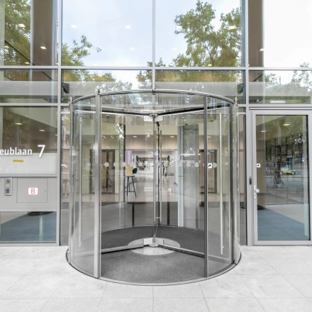 Exterior view of the office building at Mr. Treublaan 7, Amsterdam Amstel, featuring a modern revolving door entrance for office space rental.
