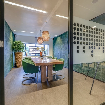 Modern furnished conference room at Prins Bernhardplein 200, Amsterdam Amstel, featuring a wooden table and green chairs, ideal for office space rental.
