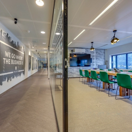 Spacious office space at Prins Bernhardplein 200, Amsterdam Amstel, with a conference room featuring green chairs and a large table, ideal for meetings. Perfect for office space rental.