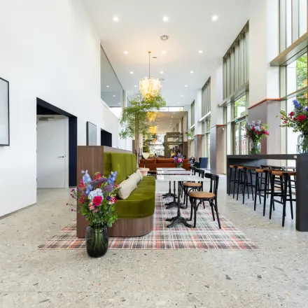 Spacious, well-lit office interior on Willem Fenengastraat 16, Amsterdam Amstel with modern seating and vibrant floral decor, perfect for office space rental.