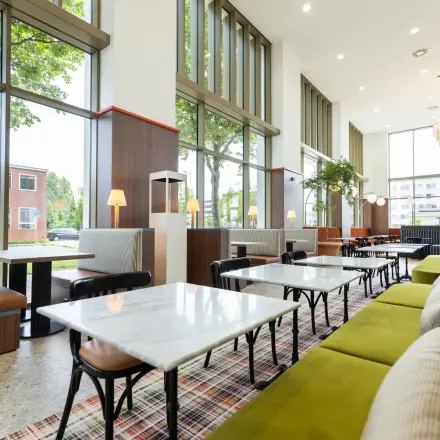 Spacious office lounge at Willem Fenengastraat 16, Amsterdam Amstel, featuring chic seating and large windows, ideal for office space rental.