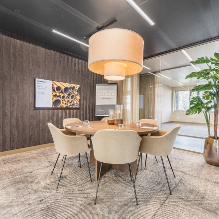 Modern office space for rent at Walborg 2A, Amsterdam Buitenveldert, featuring a meeting room with a round table, chairs, a large plant, and stylish lighting.