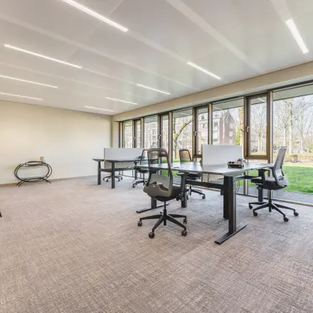 Bright office space with large windows at Walborg 2A, Amsterdam Buitenveldert, featuring modern desks and chairs available for rent.