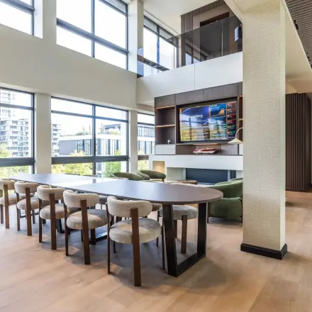 Bright workspace in Amsterdam Buitenveldert featuring a large table with chairs, overlooking an urban view through floor-to-ceiling windows, ideal for office space rental.