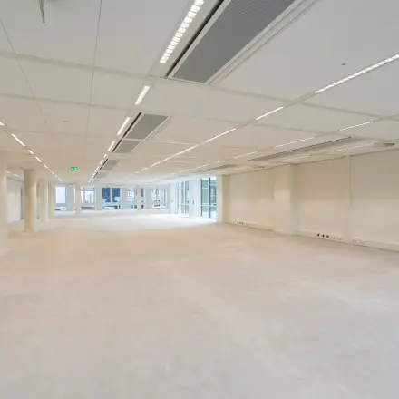 Spacious unfurnished office space available for rent at Herengracht in Amsterdam Canal Belt, featuring bright lighting and large windows.