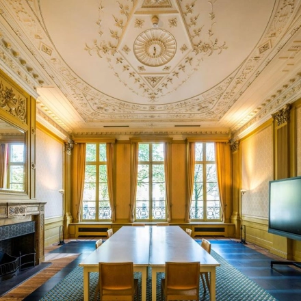 Elegant office space with ornate ceiling and large windows at Herengracht 582-584, Amsterdam Canal Belt, perfect for office space rental. Furnished with a long table and chairs, ideal for meetings.
