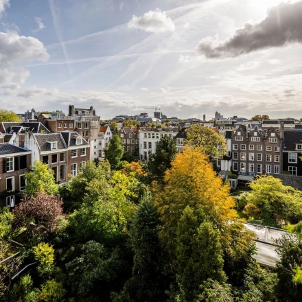 Scenic view from Herengracht 582-584 in the Amsterdam Canal Belt, showcasing surrounding historic buildings and lush greenery.